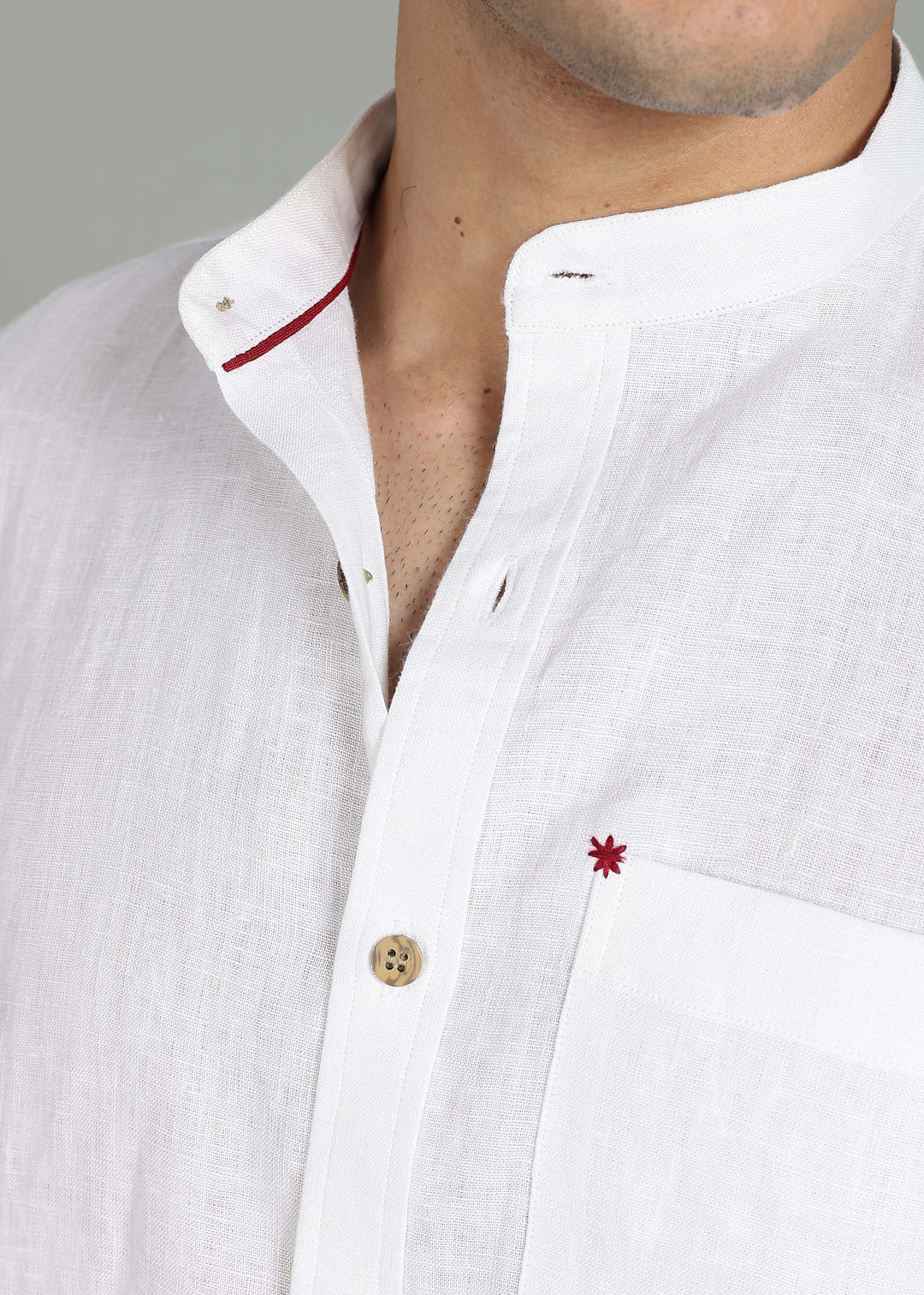 Close-up of a 100% pure linen white full sleeve shirt in 44 LEA with red detail on a gray background