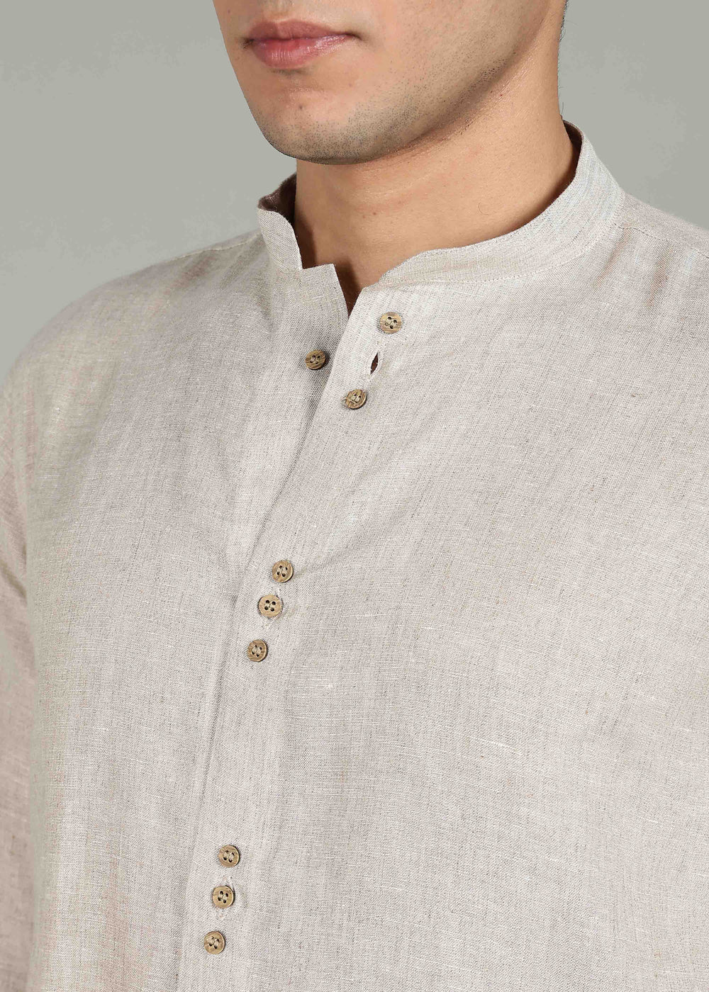 Close-up of a 100% pure linen ecru full sleeve shirt in 60 LEA with wooden buttons on a plain background