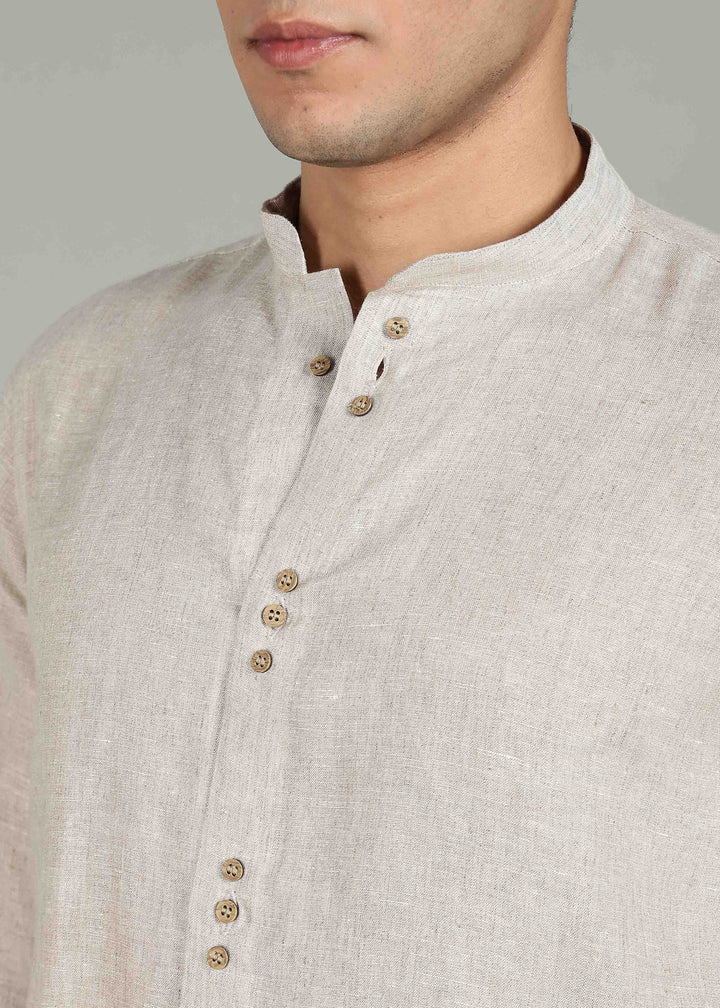Close-up of a 100% pure linen ecru full sleeve shirt in 60 LEA with wooden buttons on a plain background