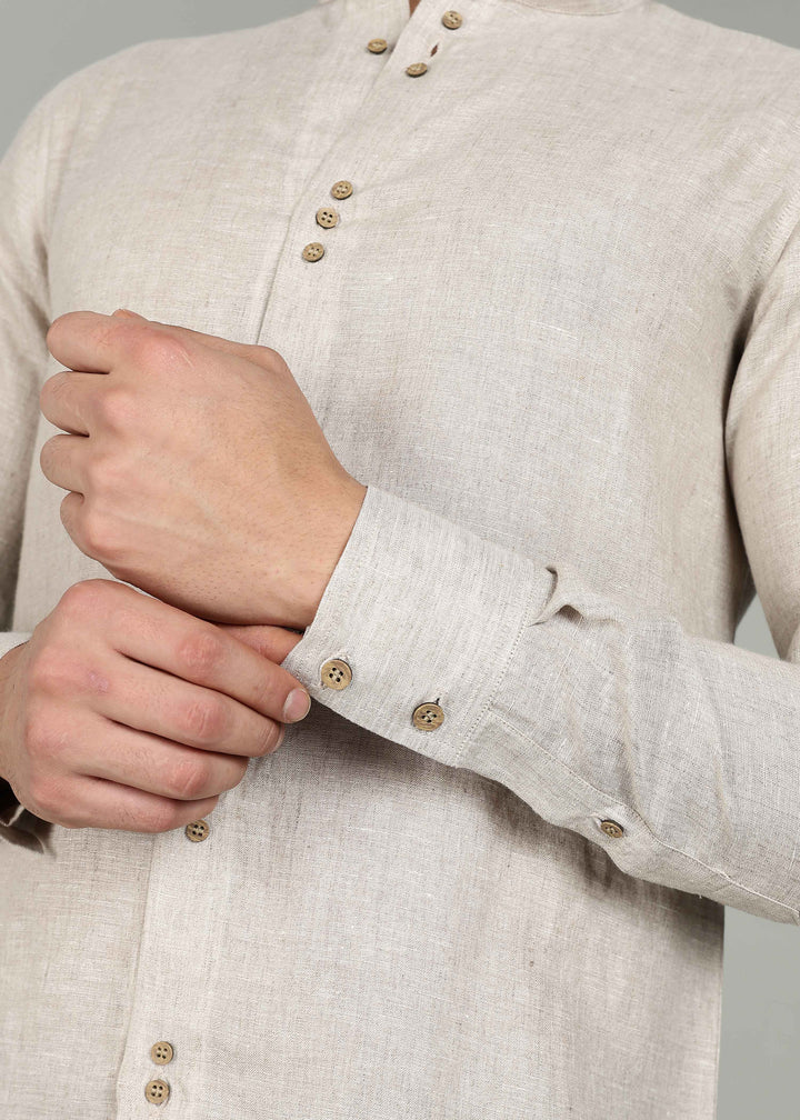 Close-up of a 100% pure linen ecru full sleeve shirt in 60 LEA with wooden buttons worn by a person.