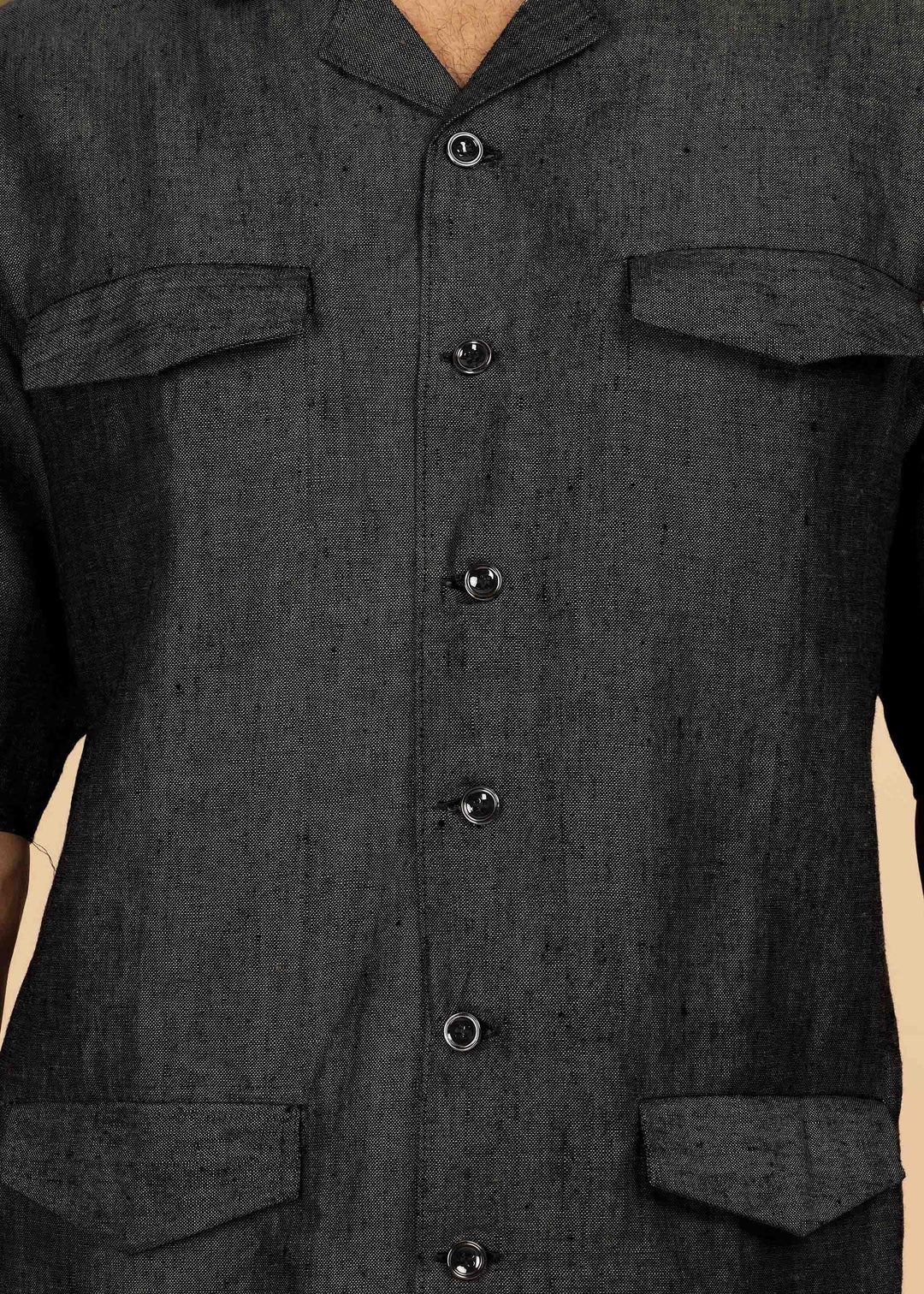 Man wearing a 100% pure linen black jacket in 25 LEA and sunglasses on a beige background