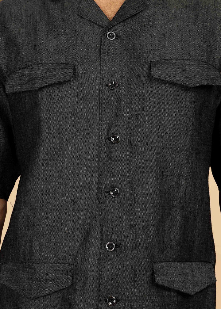 Man wearing a 100% pure linen black jacket in 25 LEA and sunglasses on a beige background