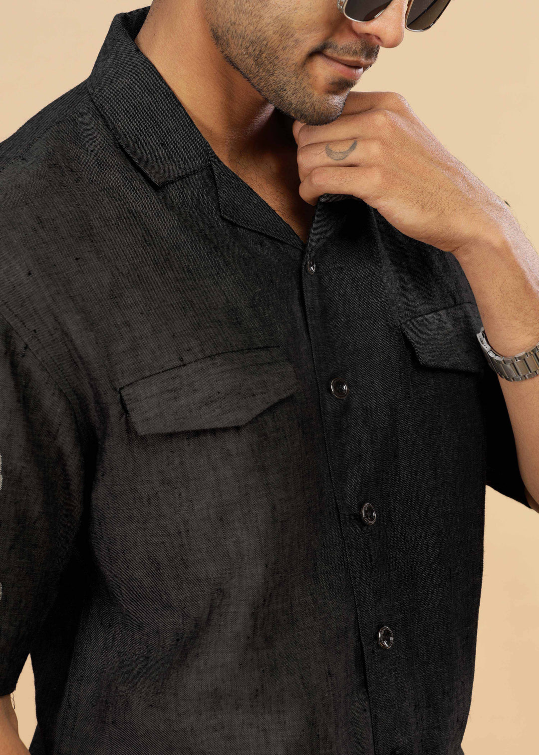 Man wearing a 100% pure linen black jacket in 25 LEA and sunglasses on a beige background