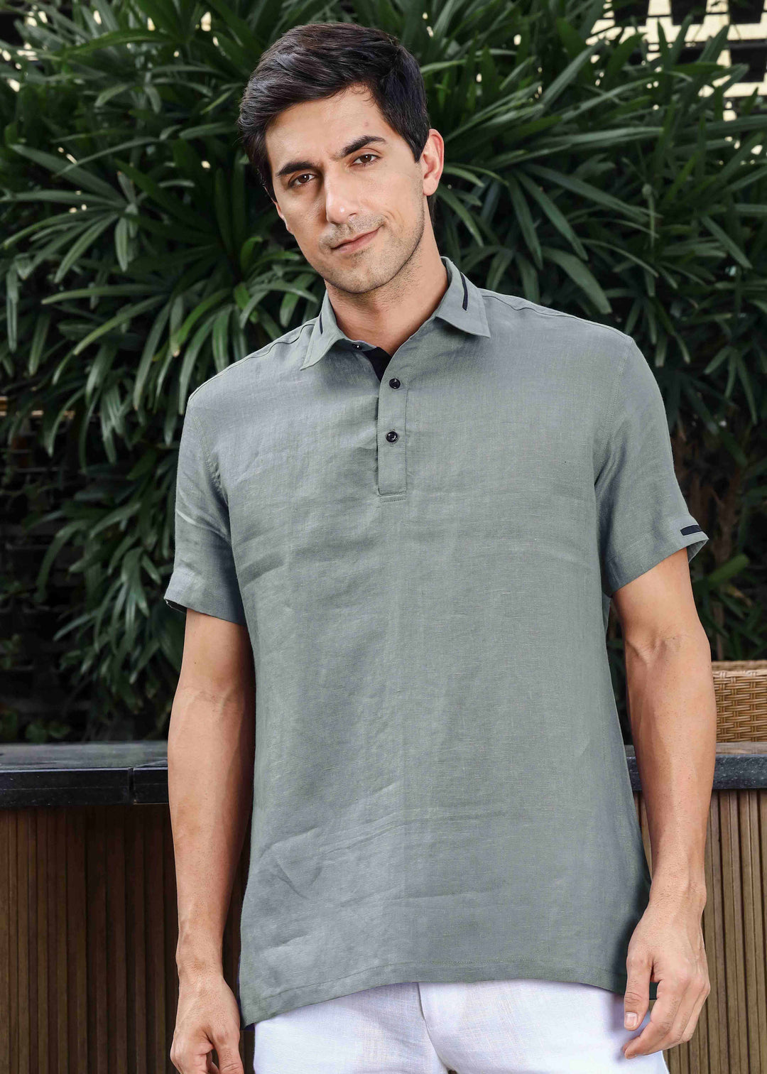 Man wearing a 100% linen gray t-shirt standing outdoors with greenery in the background