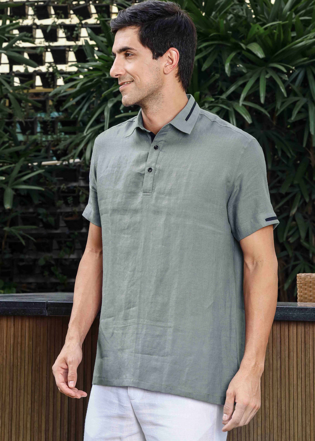 Man wearing a 100% pure linen gray t-shirt standing outdoors with greenery in the background