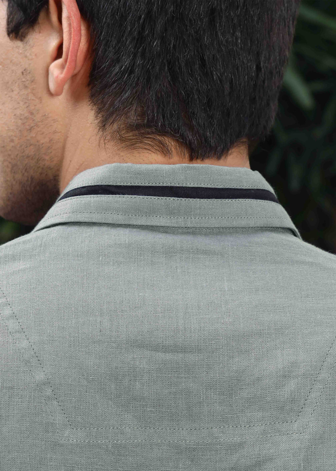 Back view of a person wearing a 100% pure linen gray t-shirt with a collar detail.