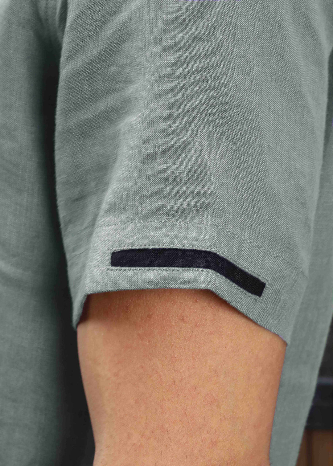 Close-up of a person wearing a 100% pure linen gray t-shirt with sleeve details.