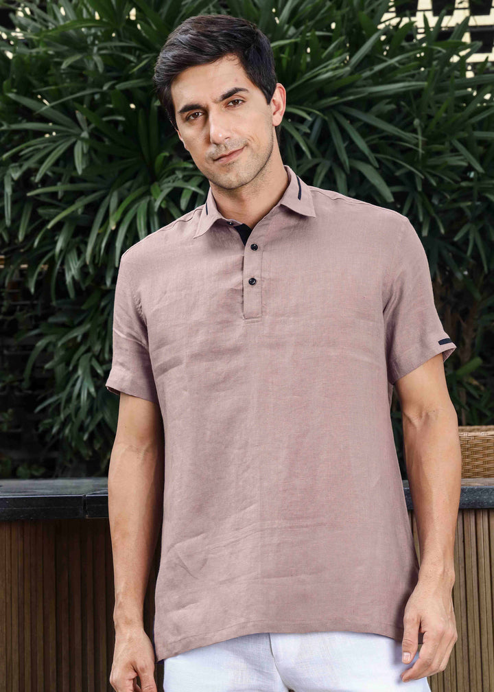 Man wearing a 100% pure linen cameo pink t-shirt standing outdoors with greenery in the background