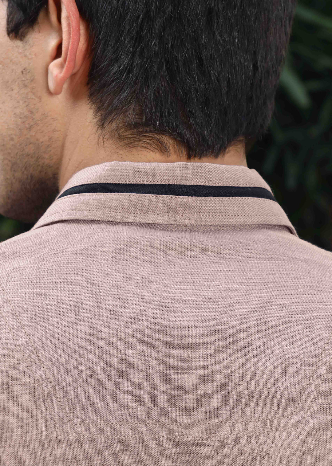 Close-up of a person wearing a 100% pure linen cameo pink t-shirt with a collar, focusing on the neck area.