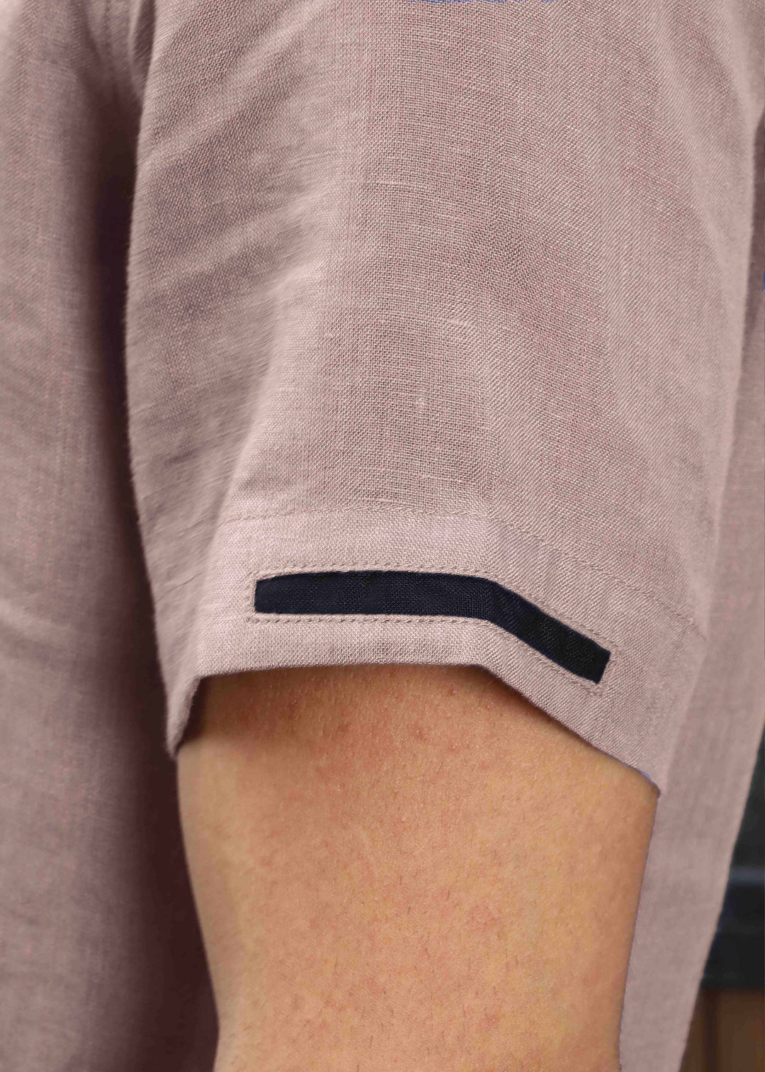 Close-up of a person wearing a 100% pure linen cameo pink t-shirt with a black trim on the sleeve cuff.