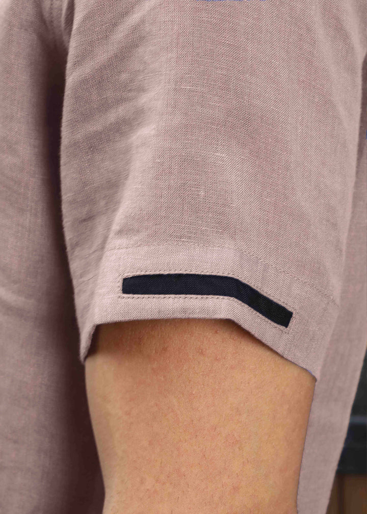 Close-up of a person wearing a 100% pure linen cameo pink t-shirt with a black trim on the sleeve cuff.