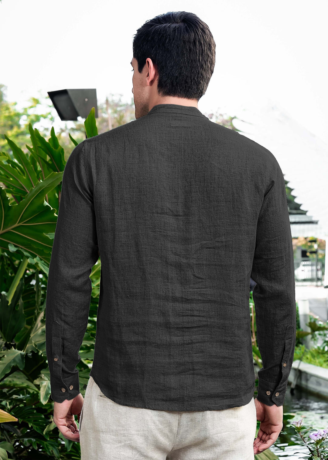 Man wearing a 100% pure linen black short kurta standing outdoors with greenery in the background