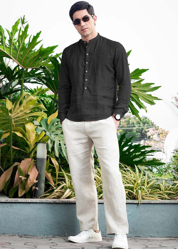 Man wearing a 100% pure linen black short kurta and white pants standing in front of green plants