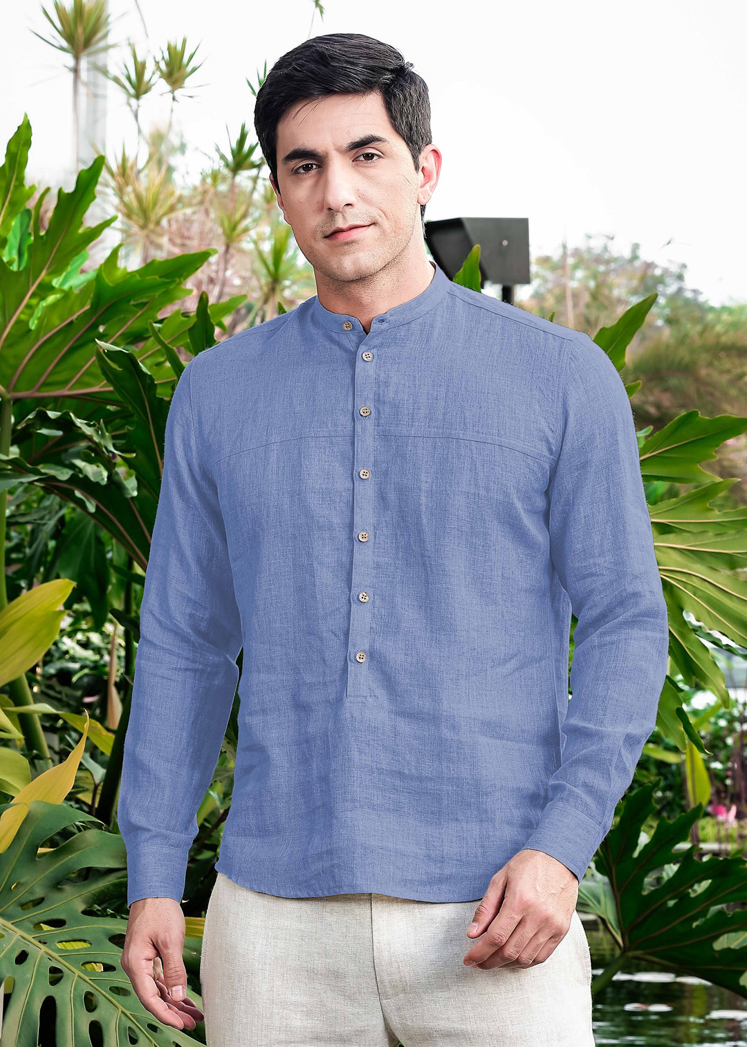 Man wearing a 100% pure linen olympic blue short kurta standing in front of green foliage
