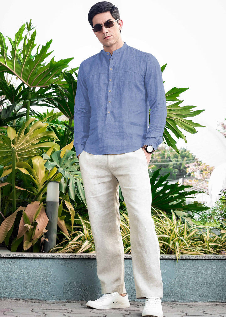 Man wearing a 100% pure linen olympic blue short kurta and white pants standing in front of green plants