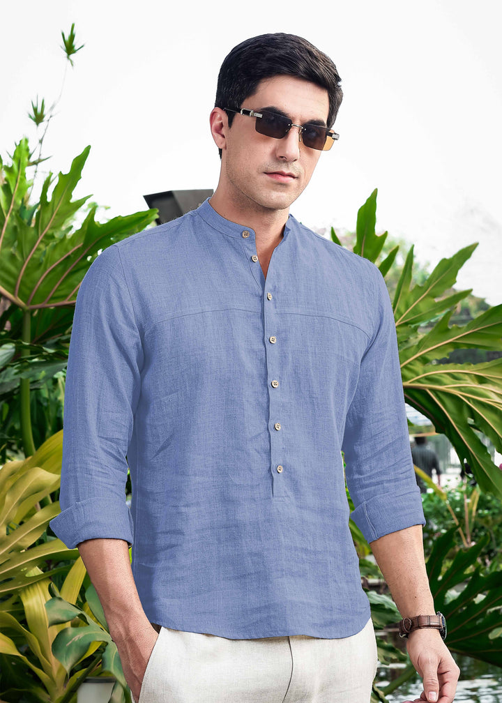 Man wearing a 100% pure linen olympic blue short kurta with sunglasses in front of green foliage