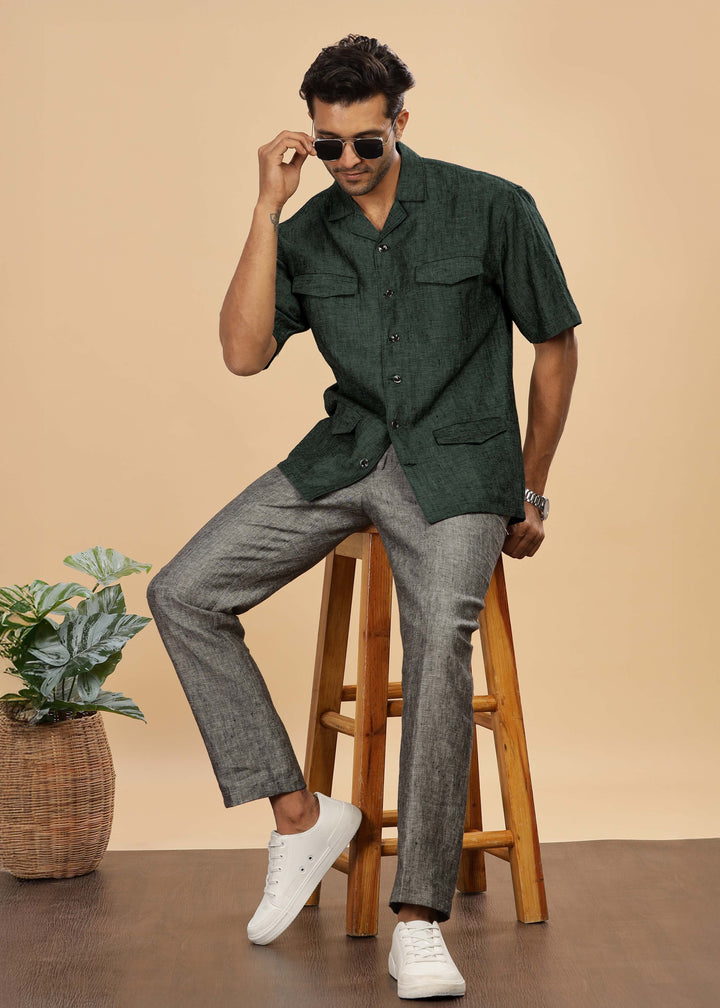Man wearing a 100% pure linen dark green jacket in 25 LEA and sunglasses on a beige background