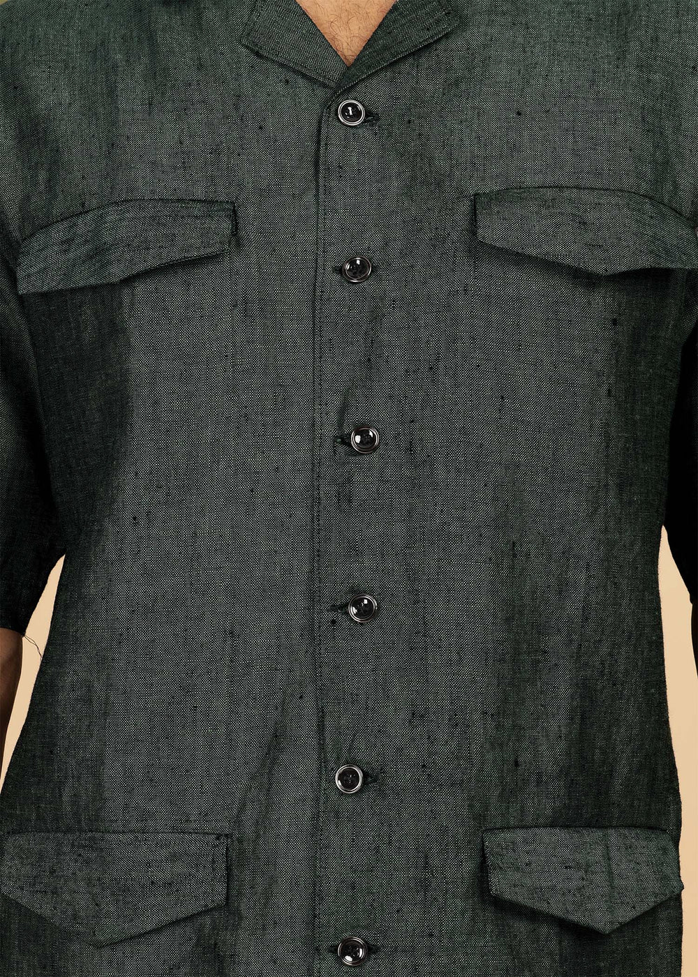 Man wearing a 100% pure linen dark green jacket in 25 LEA and sunglasses on a beige background
