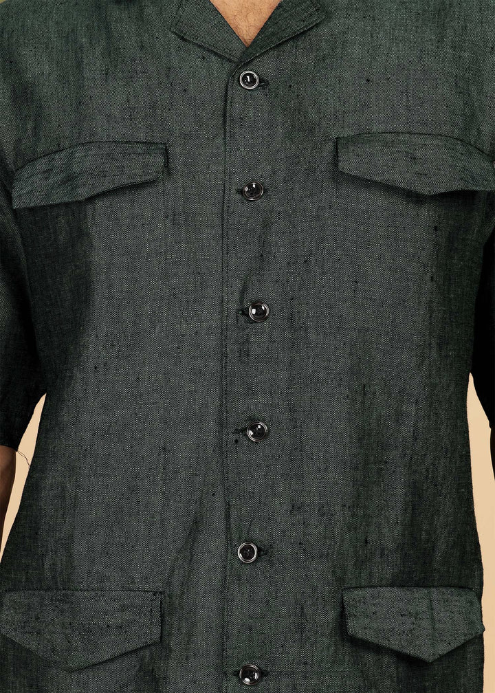Man wearing a 100% pure linen dark green jacket in 25 LEA and sunglasses on a beige background