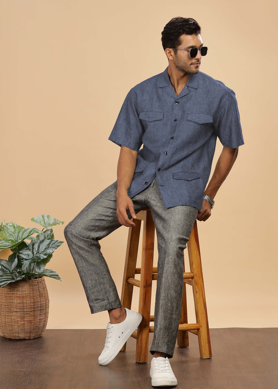 Man wearing a 100% pure linen dark blue grey jacket in 25 LEA and sunglasses on a beige background