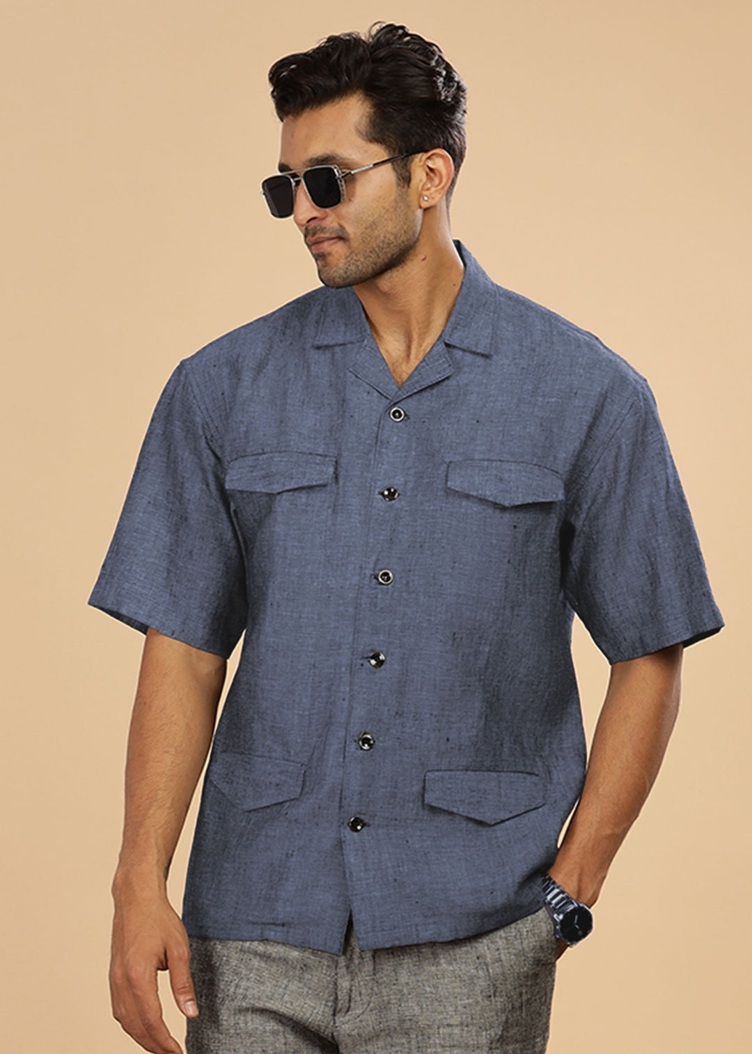Man wearing a 100% pure linen dark blue grey jacket in 25 LEA and sunglasses on a beige background