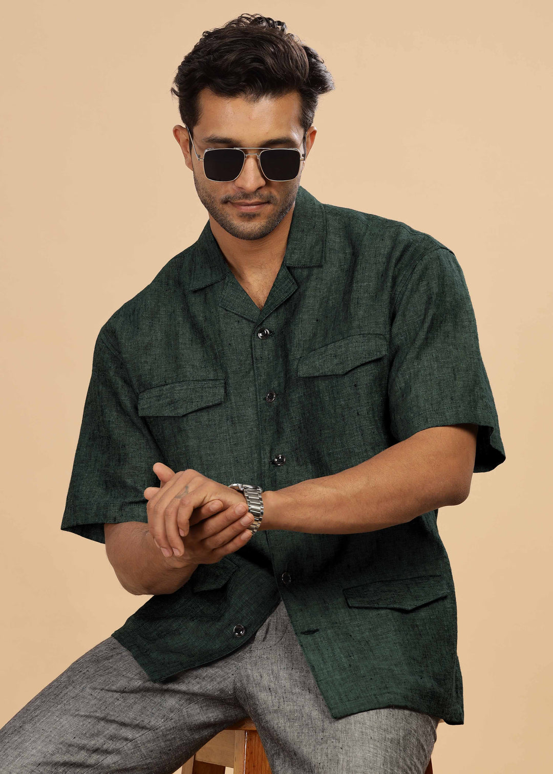 Man wearing a 100% pure linen dark green jacket in 25 LEA and sunglasses on a beige background