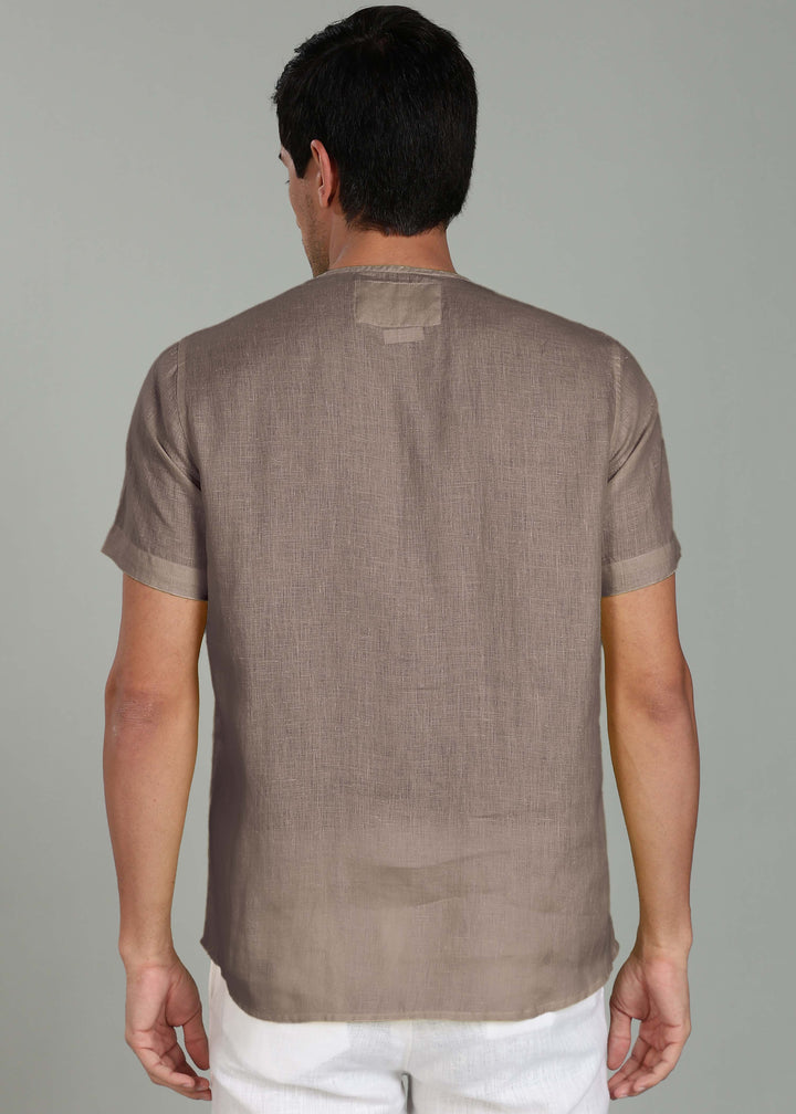 Man wearing a 100% pure linen fawn pink t-shirt against a gray background
