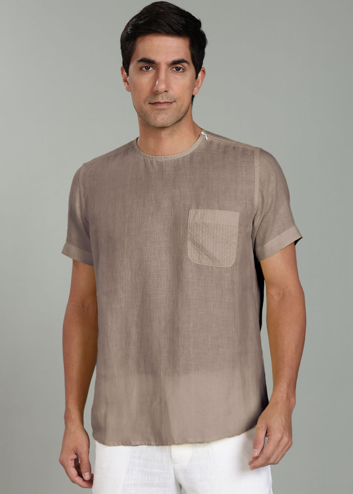 Man wearing a 100% pure linen fawn pink t-shirt with a pocket on a gray background