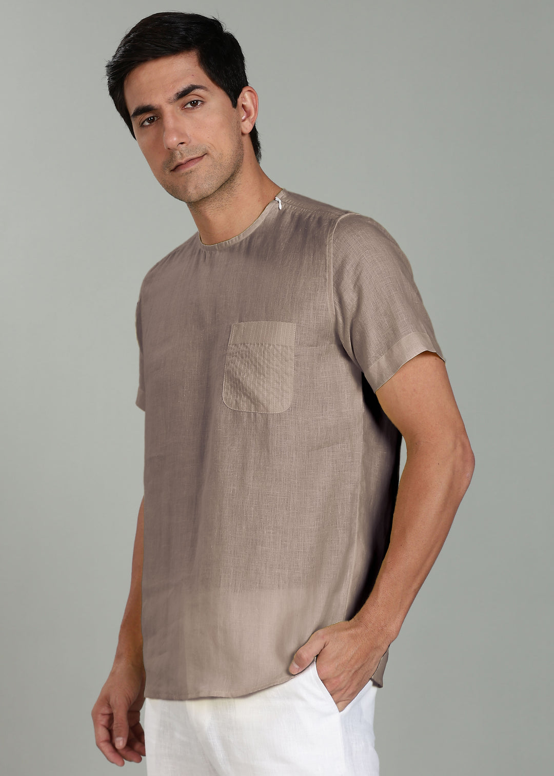 Man wearing a 100% pure linen fawn pink t-shirt with a pocket on a gray background