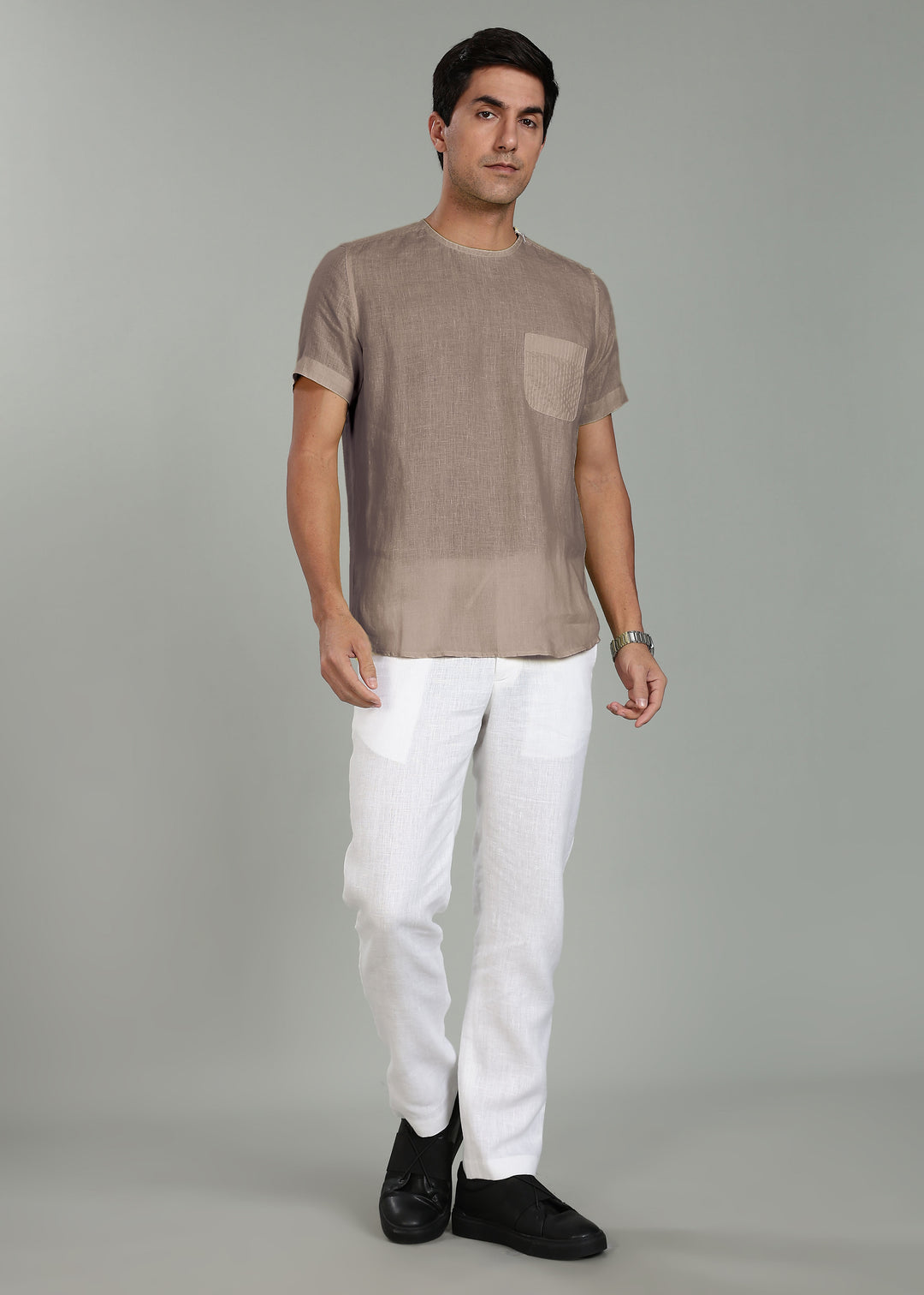 Man wearing a 100% pure linen fawn pink t-shirt and white pants on a gray background