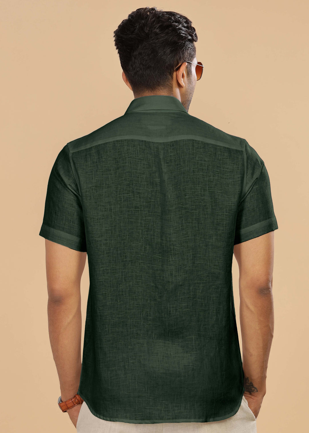Man wearing a 100% pure linen dark fern green shirt against a beige background