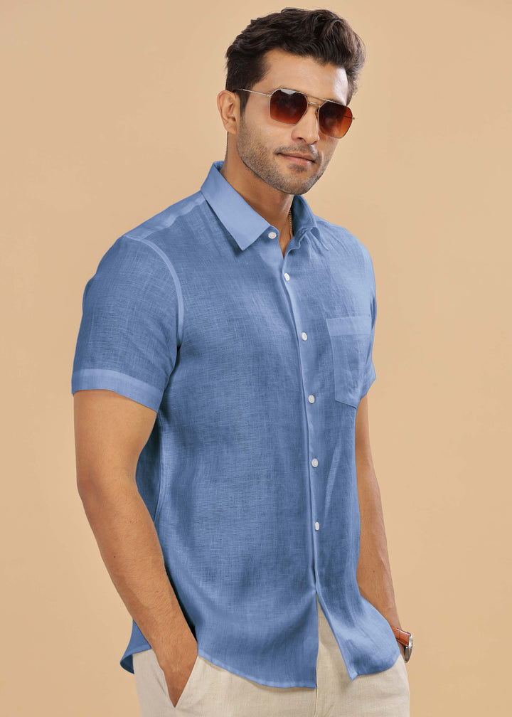 Man wearing a 100% pure linen olympic blue shirt and sunglasses on a beige background