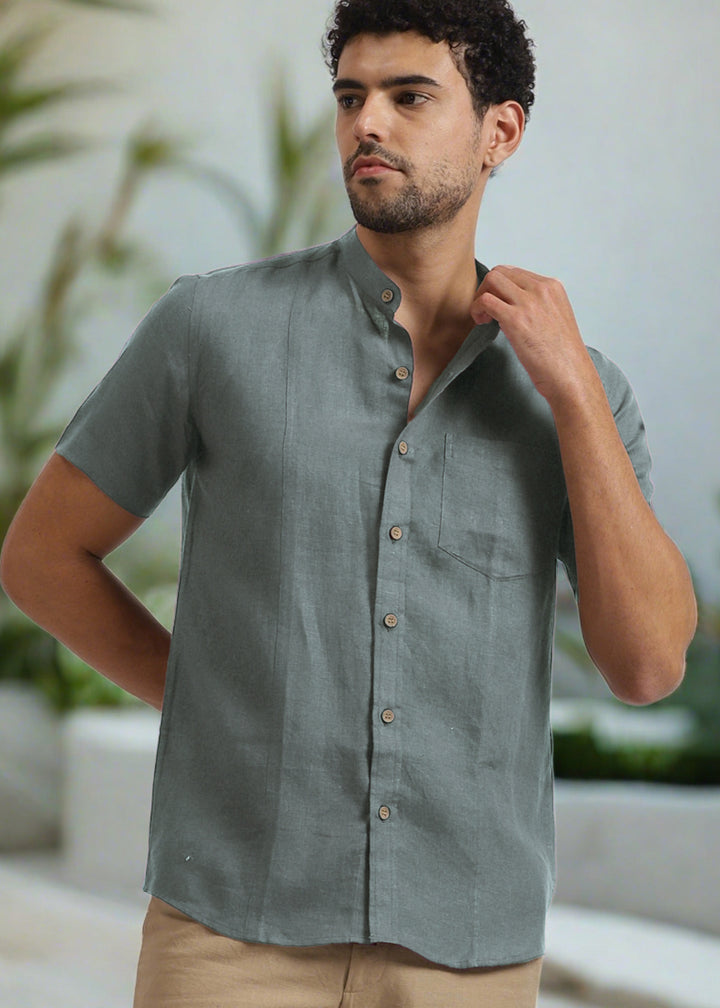 Man wearing a 100% pure linen mineral grey shirt outdoors with plants in the background