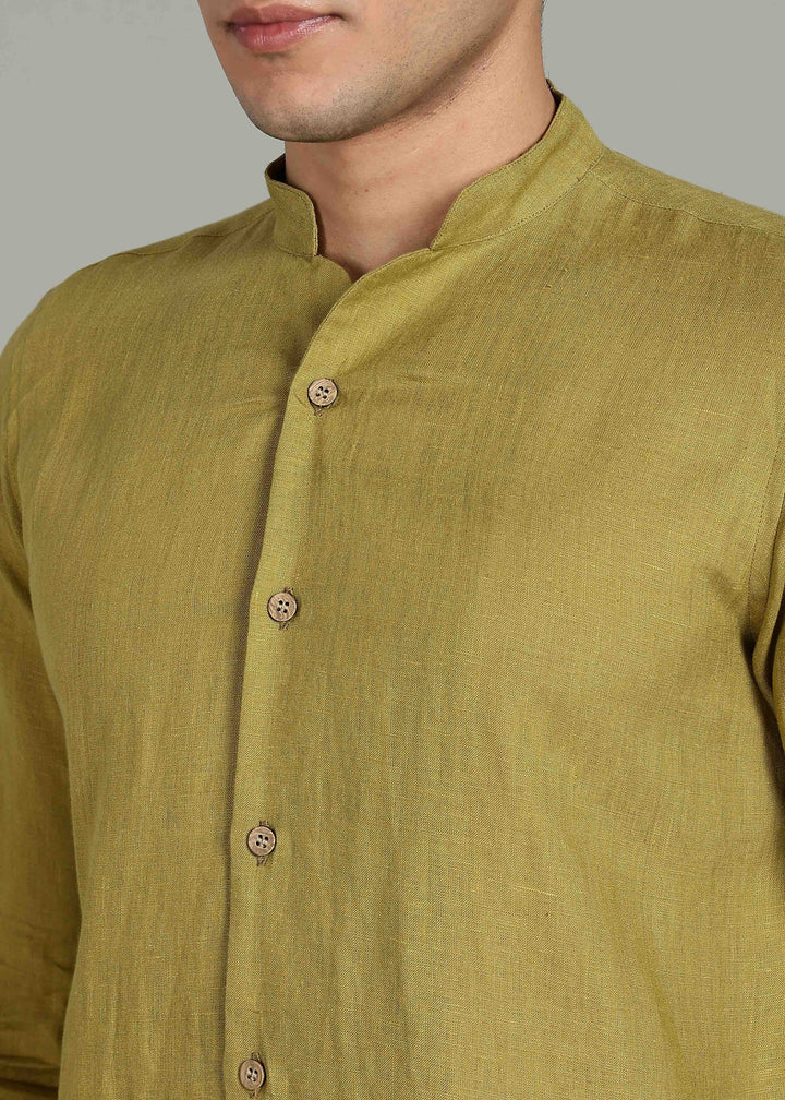 Close-up of a person wearing a 100% pure linen sap green full sleeve shirt in 60 LEA with buttons on a plain background